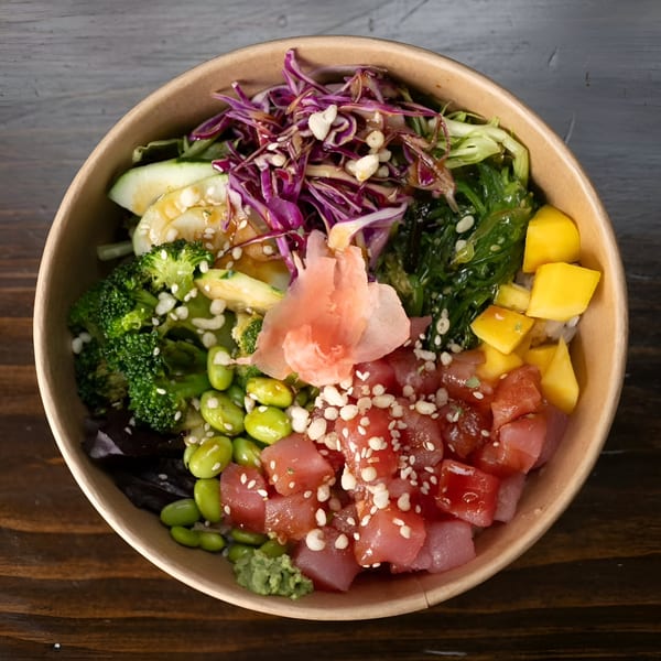 Top-down view of a colorful Yum Yubu poke bowl with tuna, mango, edamame, and purple cabbage.