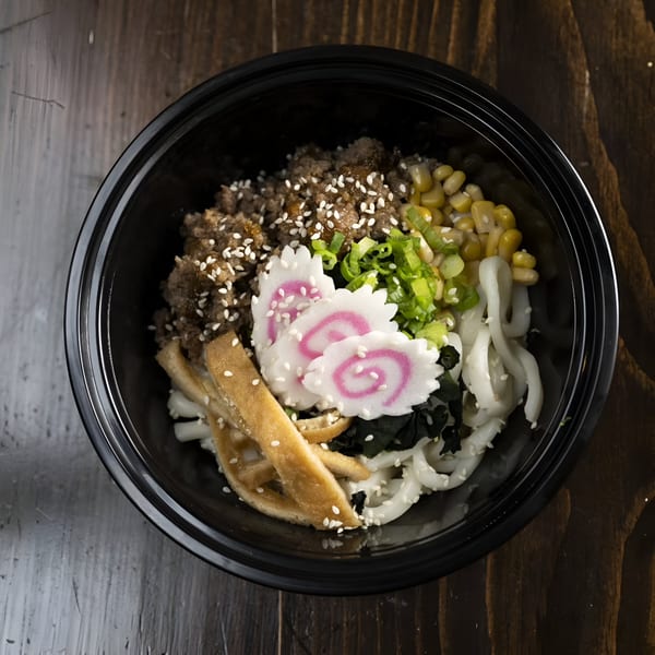 Yum Yubu poke bowl with ground meat, corn, green onions, fish cakes, and noodles.
